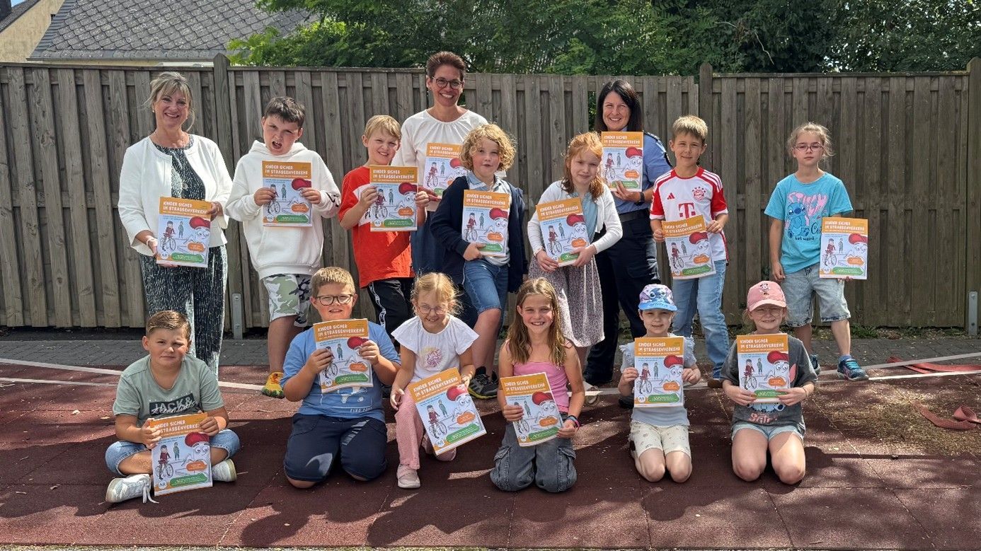 Gruppenfoto von Schülerinnen und Schülern, die ein Arbeitsheft über das sichere Radfahren in der Hand halten.