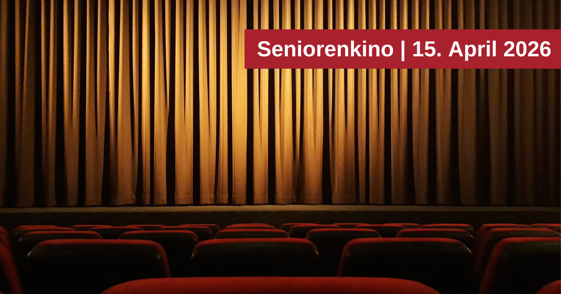Das Bild zeigt einen Kinosaal mit roten Sitzen im Vordergrund und einem geschlossenen goldenen Vorhang im Hintergrund. Über dem Vorhang befindet sich ein roter Balken mit der weißen Aufschrift "Seniorenkino | 15. April 2026".