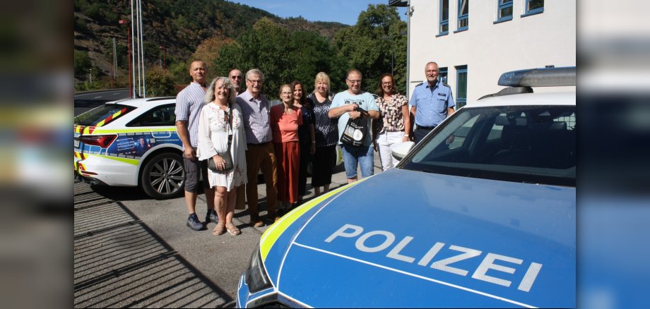 Sicherheitsberaterinnen und Sicherheitsberater aus dem Landkreis Cochem-Zell Eine Gruppe von Menschen steht vor zwei Polizeifahrzeugen vor der Polizeidienststelle Cochem.