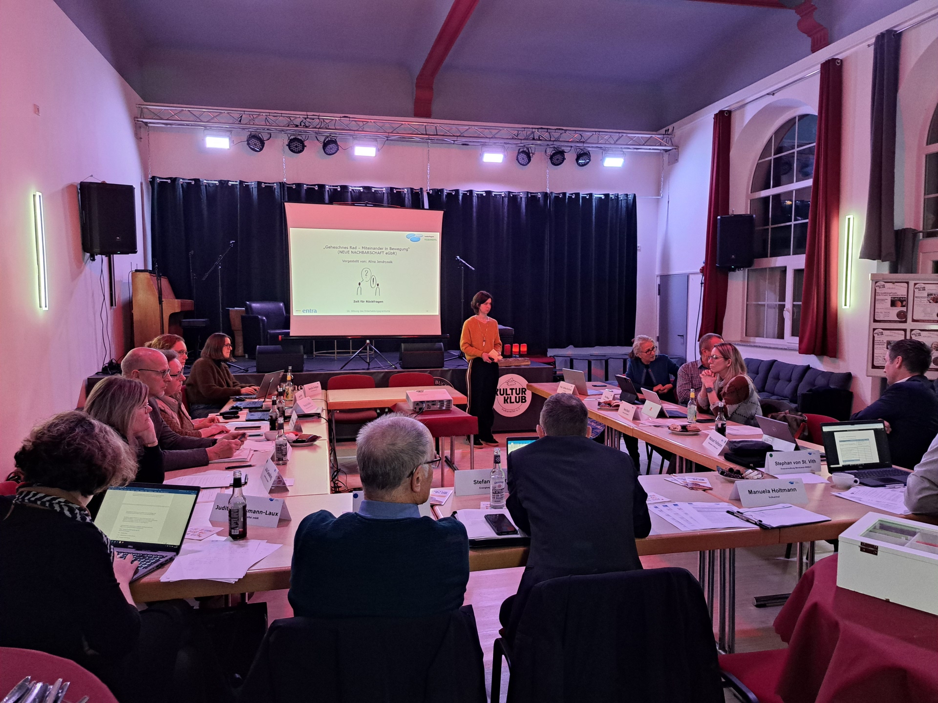 Das Foto zeigt zwölf Frauen und Männer, die bei der 10. Sitzung der Lokalen Aktionsgruppe Leader einer Referentin zuhören. 