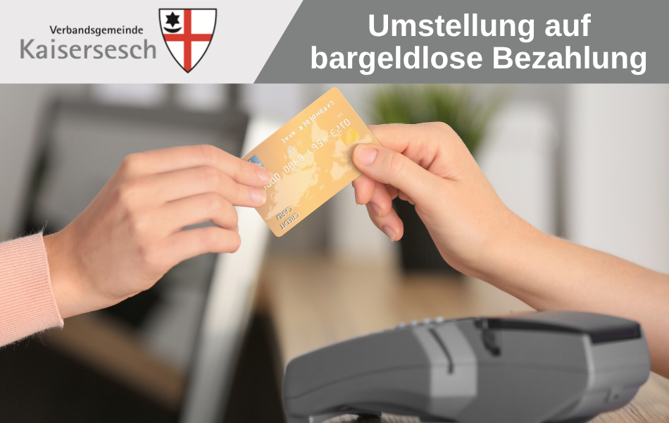 Das Bild zeigt zwei Hände, die eine Kreditkarte gemeinsam halten. Das graue Bezahlgerät unterhalb der Hände hat mehrere Knöpfe und einen Bildschirm. Die Kreditkarte ist goldfarben und hat einige Zahlen und Buchstaben gedruckt. Der Hintergrund ist unscharf und zeigt eine helle Wand und eine grüne Pflanze. Oben links auf dem Bild befindet sich ein Logo mit der Aufschrift „Verbandsgemeinde Kaisersesch“ und einem Wappen. Oben rechts steht in großen weißen Buchstaben „Umstellung auf bargeldlose Bezahlung“. Die Farben im Bild sind hell und freundlich, mit einem Fokus auf die goldene Kreditkarte. Die Komposition ist eng und auf die Interaktion der Hände mit der Karte fokussiert, was die Botschaft der bargeldlosen Zahlung unterstreicht.  