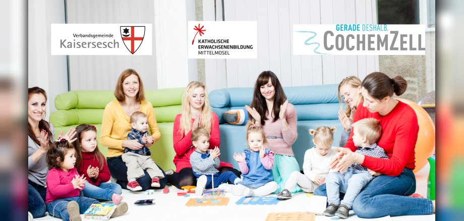 Das Bild zeigt eine Gruppe von Frauen und kleinen Kindern, die lächelnd und klatschend auf dem Boden sitzen. Im Hintergrund sind Sofas zu sehen. Oben im Bild sind drei Logos platziert: eines mit der Aufschrift „Verbandsgemeinde Kaisersesch“, ein weiteres mit „Katholische Erwachsenenbildung Mittelmosel“ und ein drittes mit „Gerade deshalb CochemZell“.  