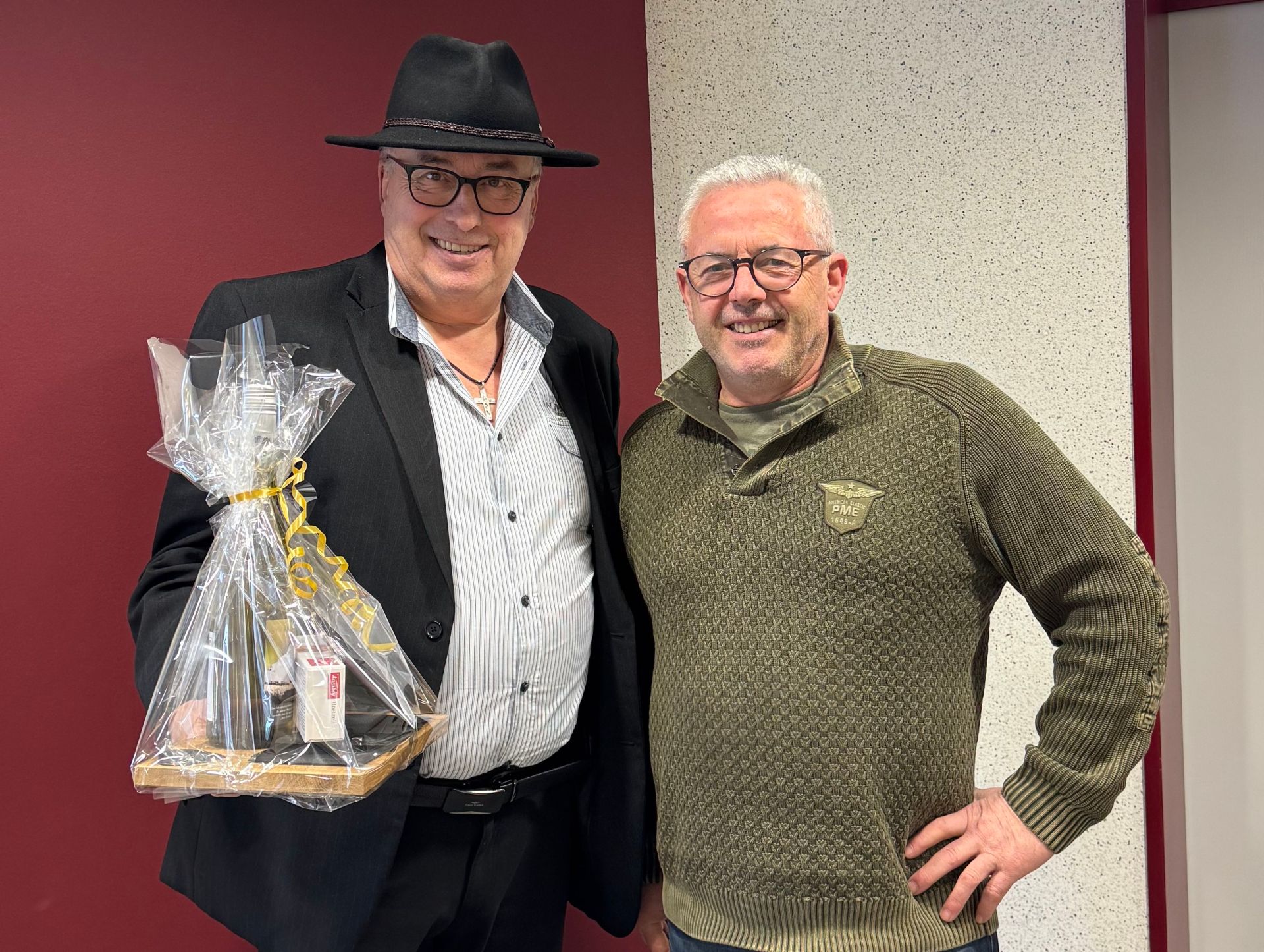 Hans-Günter Labonte und Bürgermeister Albert Jung stehen stehen gemeinsam vor einer rot-weißen Wand. Herr Labonte hält ein Präsent in der Hand.