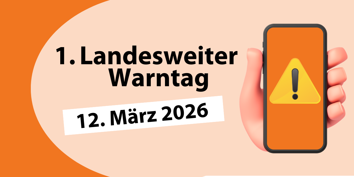 Hinweis zum landesweiten Warntag am 12. März 2026. Das Foto  zeigt auf der rechten Seite eine Hand, die ein Smartphone hält, auf dem ein gelbes Dreieck und ein Fragezeichen abgebildet sind. Auf der linken Seite steht "1. Landesweiter Wantag" und das Datum 12. März 2026.