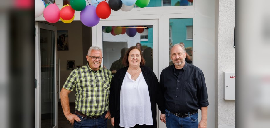 Gratulation zum 15-jährigen Bestehen der Tierarztpraxis Mantek Drei Personen stehen lächelnd vor einem Hauseingang, der mit bunten Luftballons geschmückt ist.