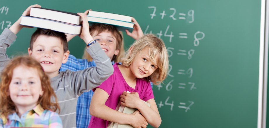 Schulkinder mit Büchern auf dem Kopf