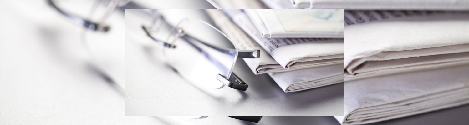 Zeitungen mit Brille auf einem Tisch Pressemitteilungen