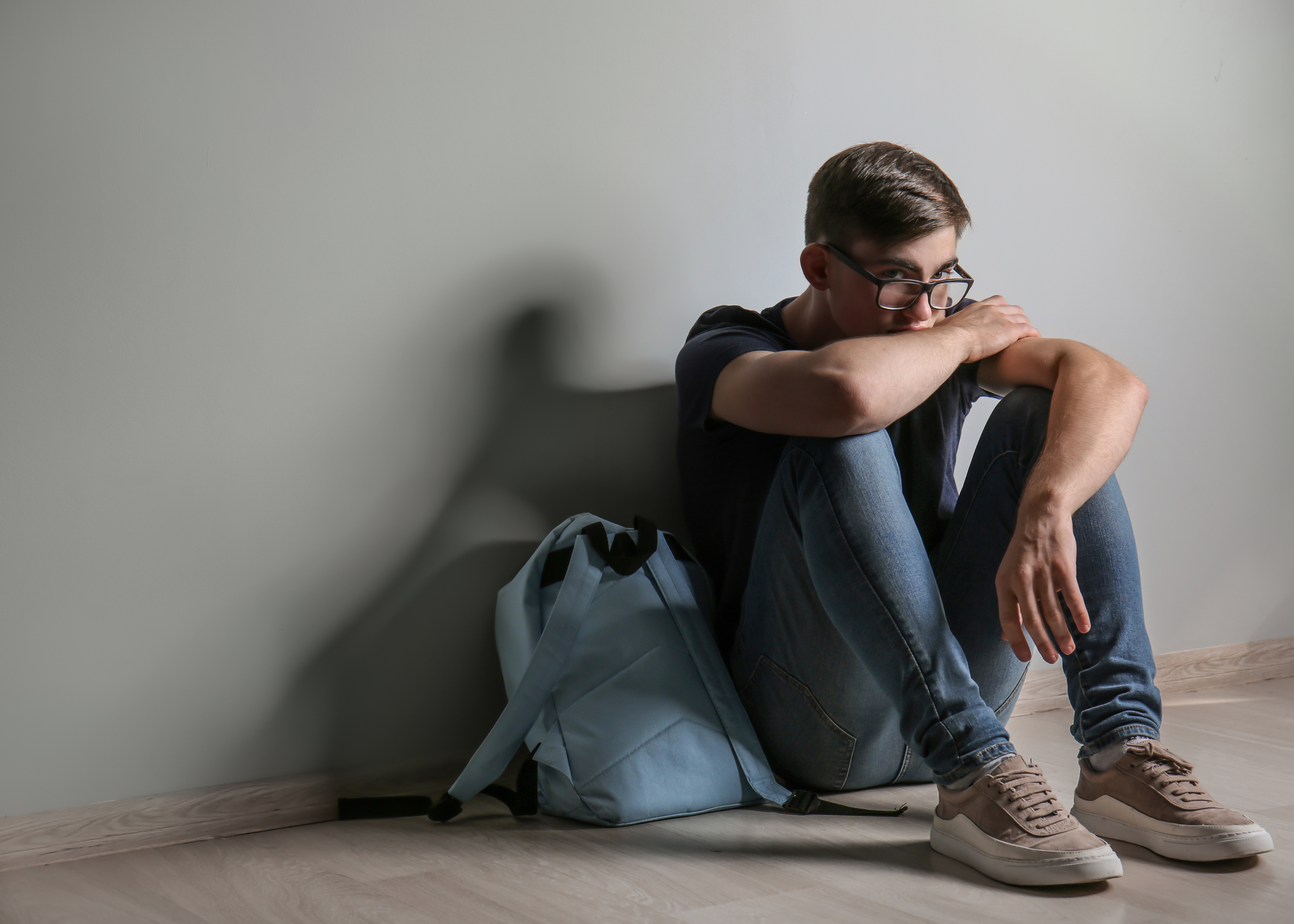 Ein junger Mann sitzt auf dem Boden eines Zimmers.